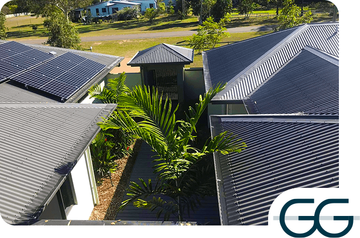 Dark metal roofs with solar panels and palms in a courtyard, GG logo in the corner